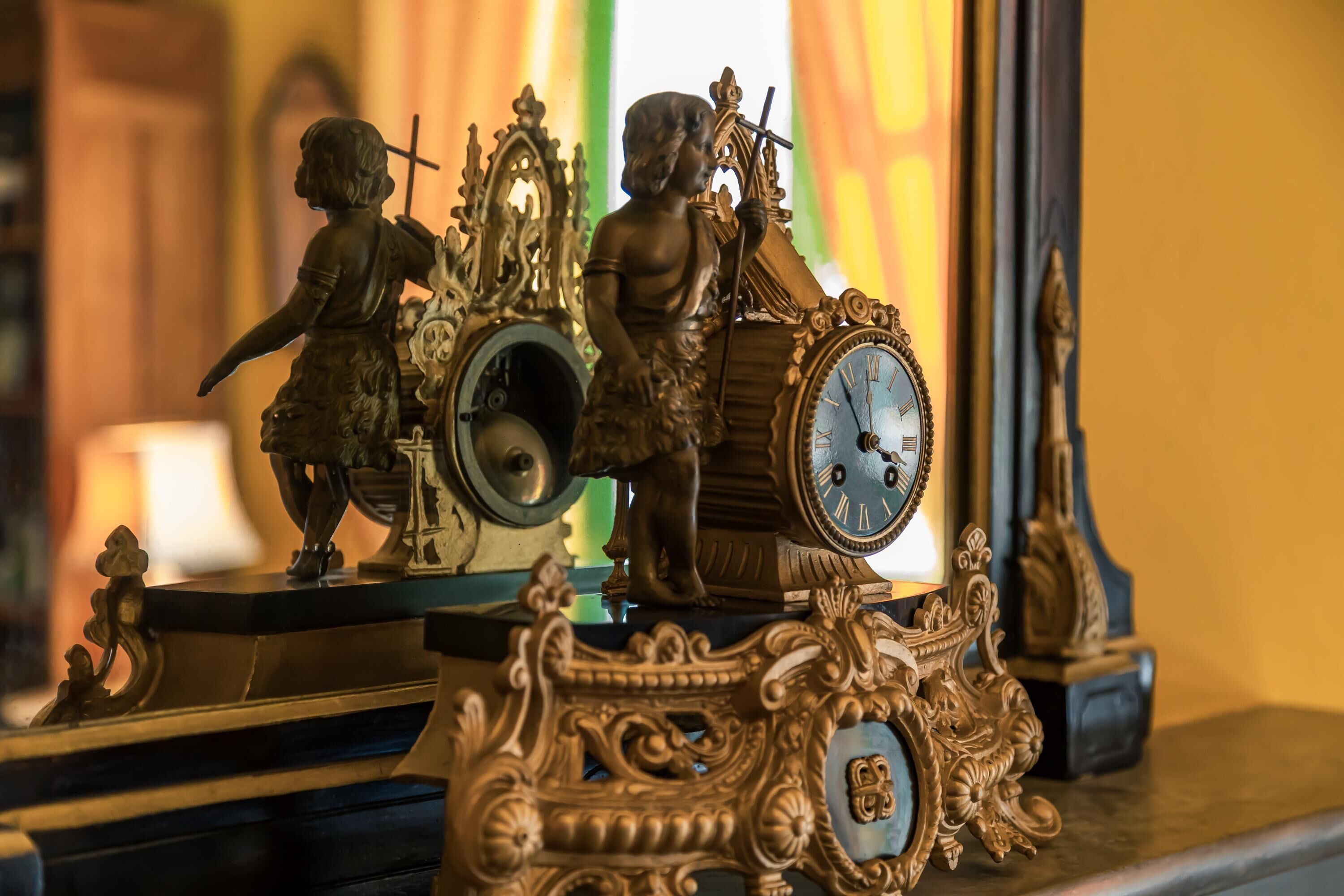 A clock with ornate carvings and two figurines on its face.