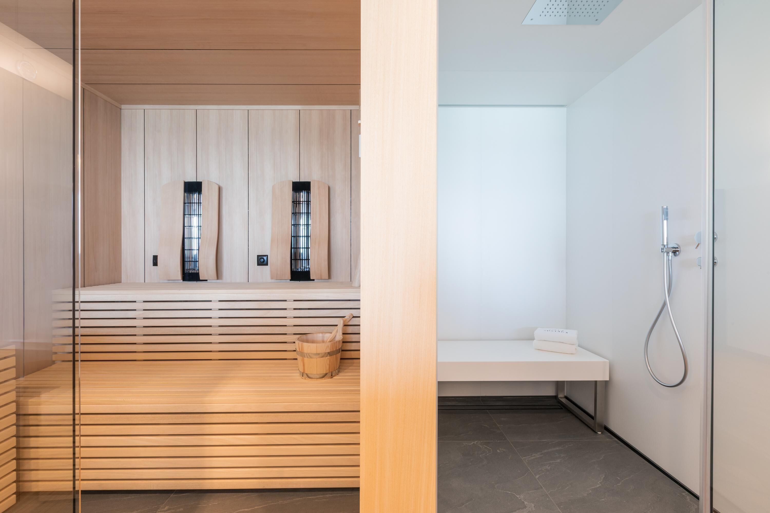 Une salle de spa moderne avec des lambris en bois, un seau en bois et un banc blanc.