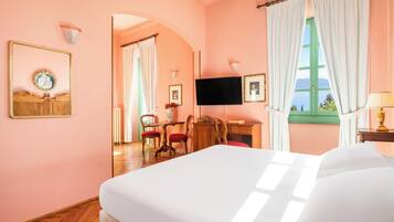 Une chambre d’hôtel avec un grand lit, un bureau avec une chaise, une télévision et une fenêtre avec des rideaux.