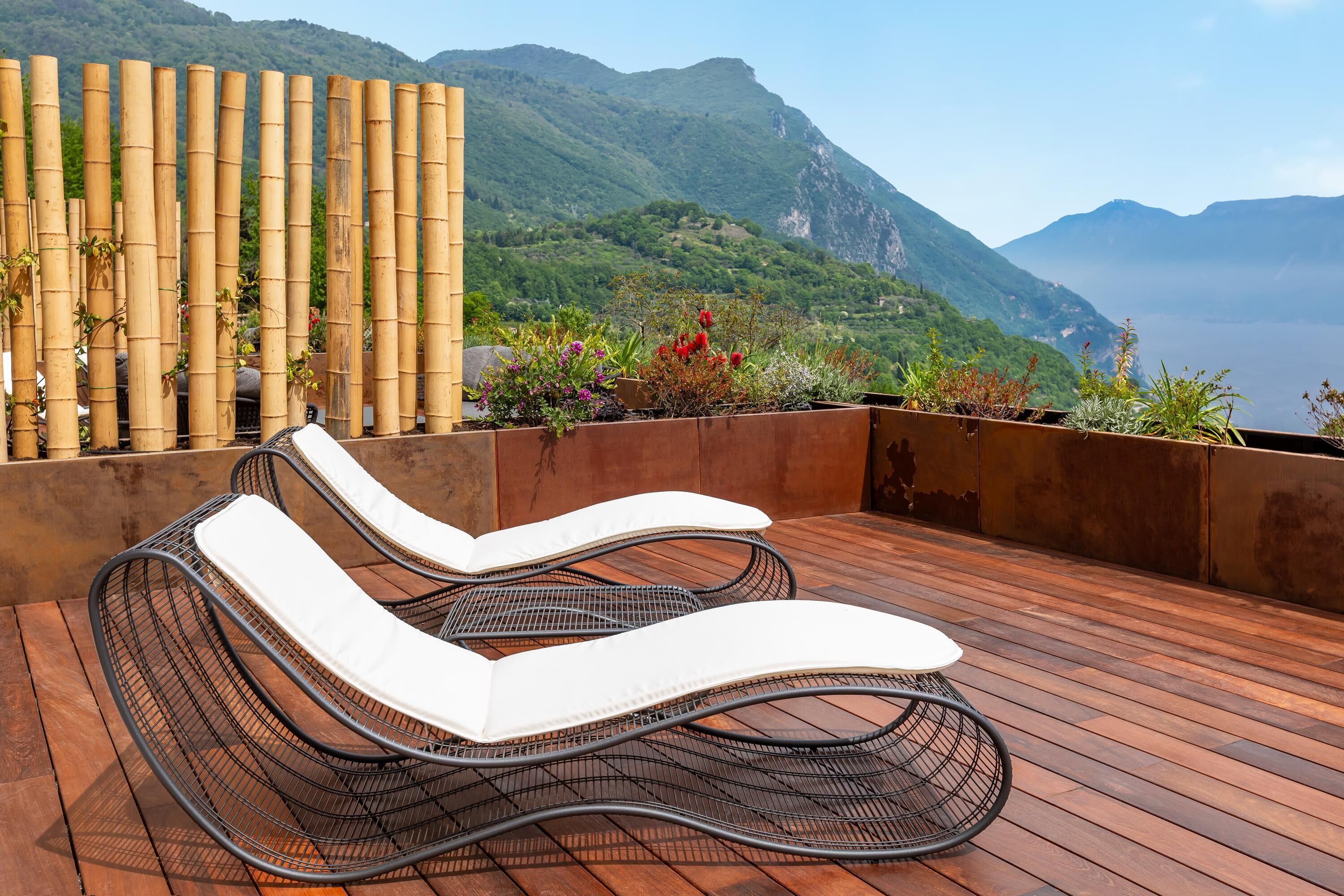 Terraza en la azotea con dos sillones de relax y una cerca de bambú, con vistas a un paisaje montañoso.