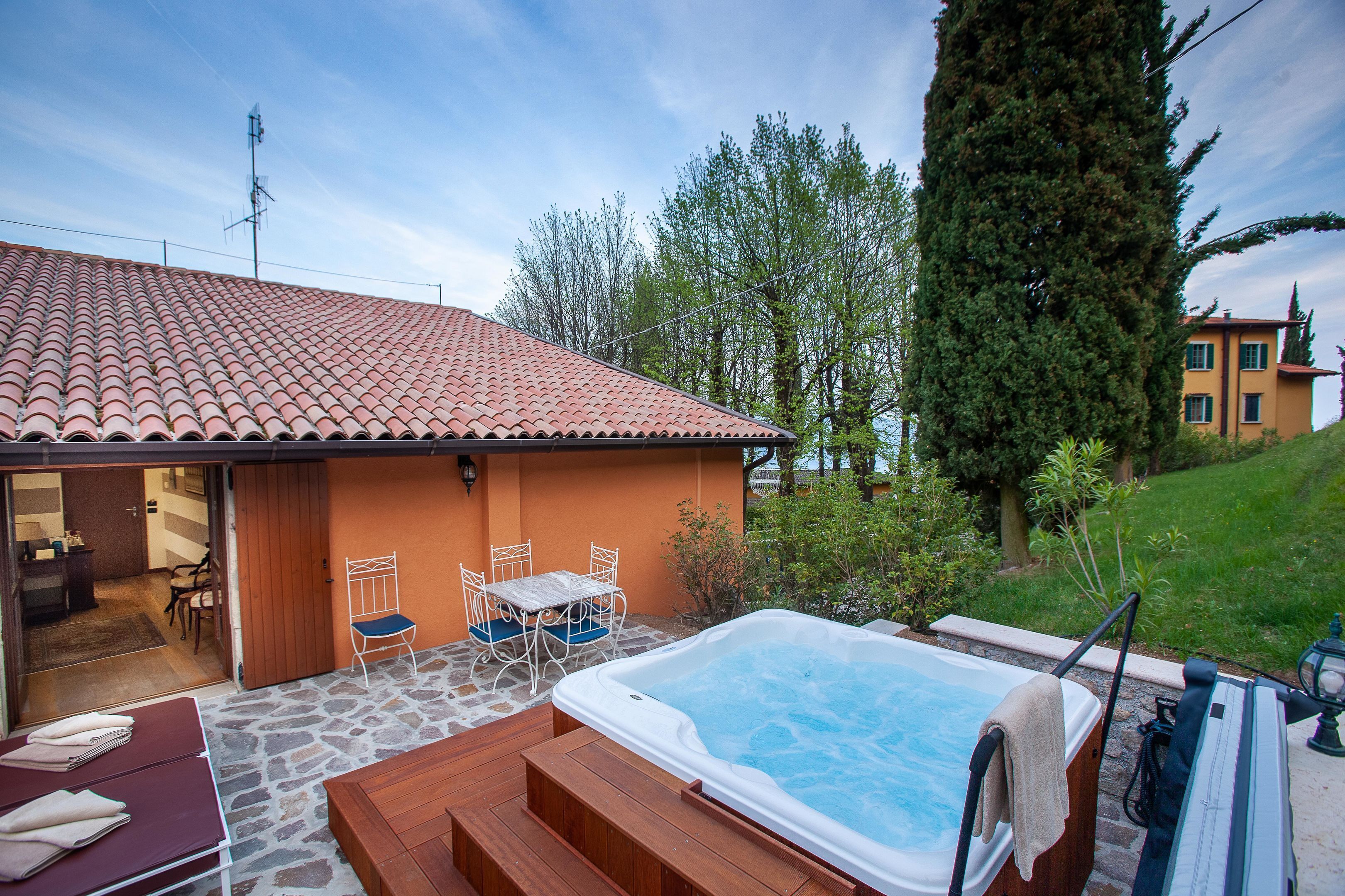 Ein Wellnessbereich mit Whirlpool, Holzterrasse und Sitzgelegenheiten im Freien.
