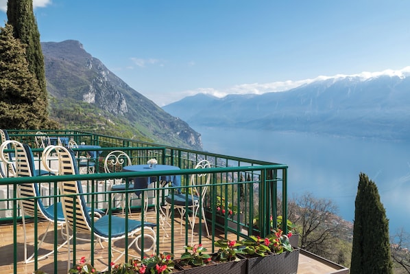 A terrace with outdoor seating, overlooking a lake and mountains.