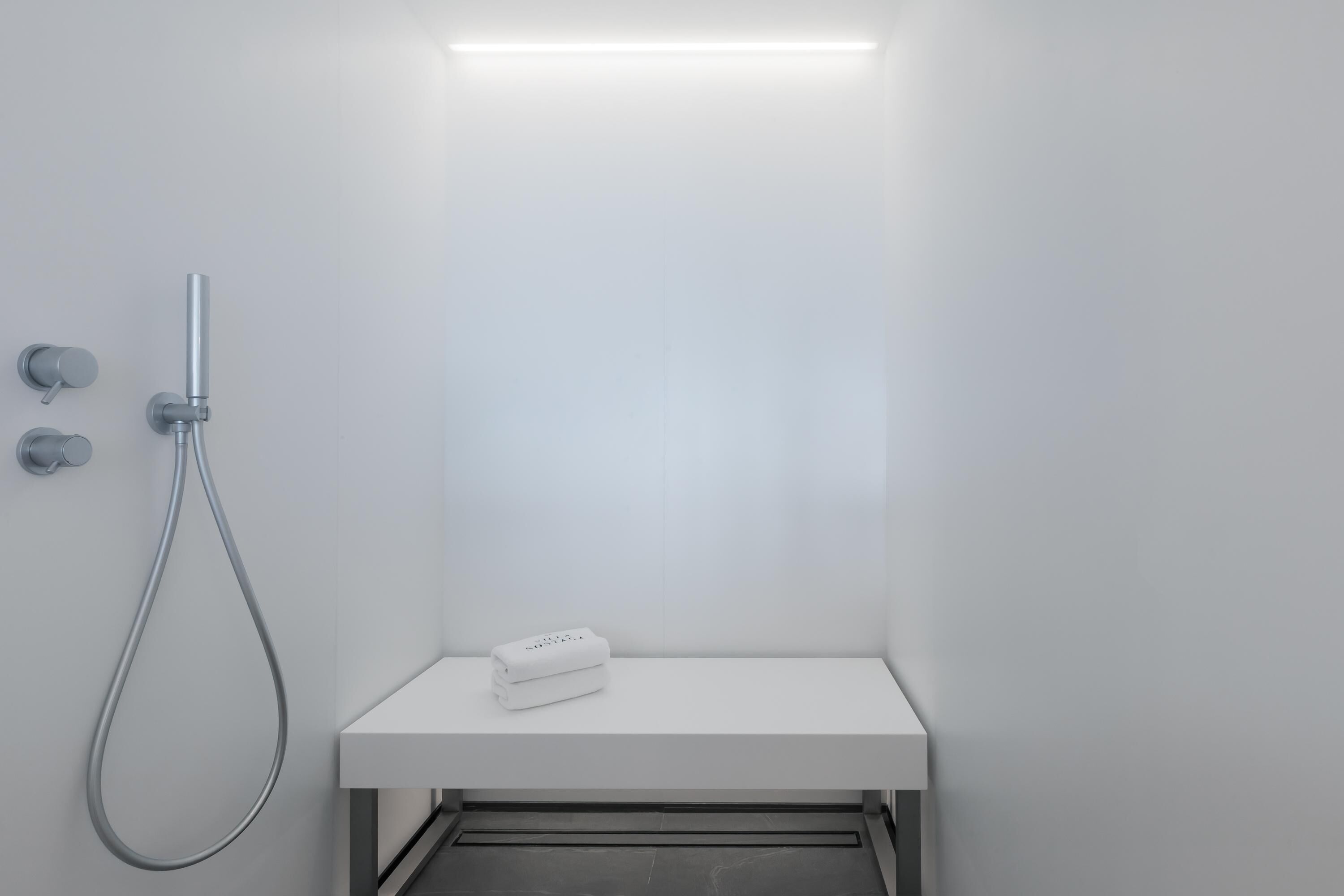 A modern bathroom with a shower, a white sink, and a towel on the counter.
