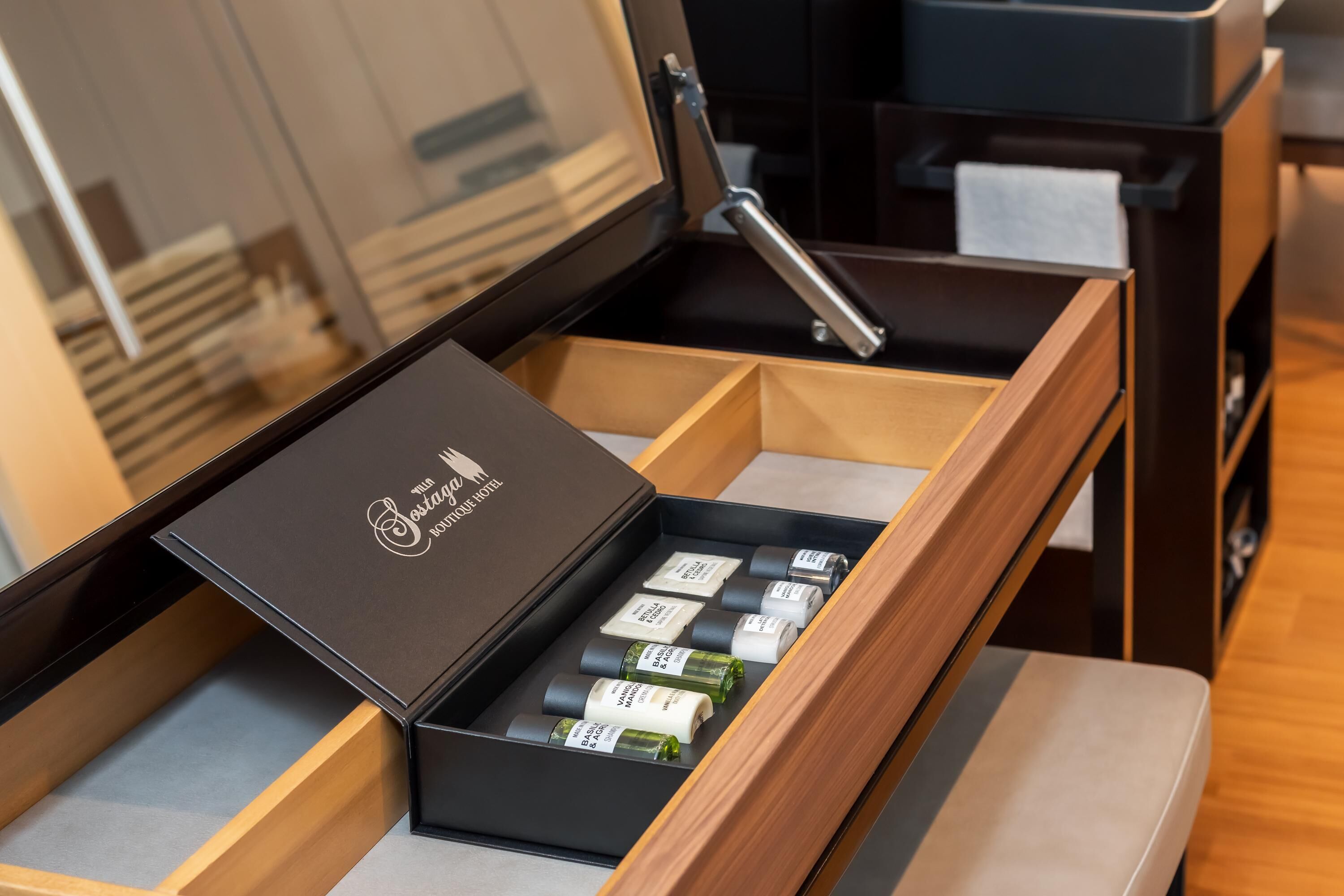 Un cassetto in legno con una scatola nera contenente diversi articoli da toilette.