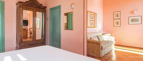 A bedroom with a large bed, a wardrobe, a mirror, and a sofa.