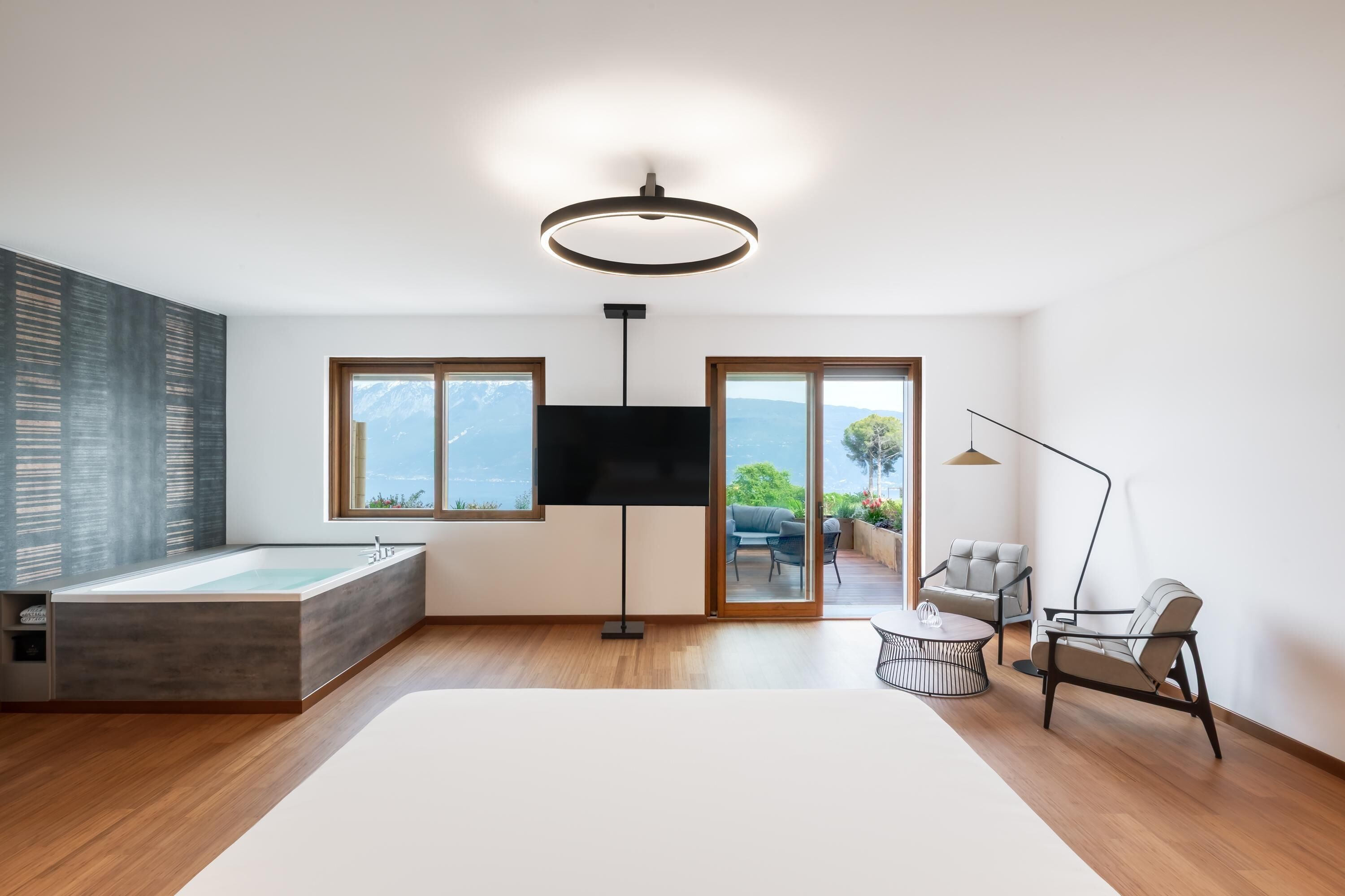 Ein modernes Wohnzimmer mit großem Fenster, Flachbildfernseher, Stehlampe und Sofa.