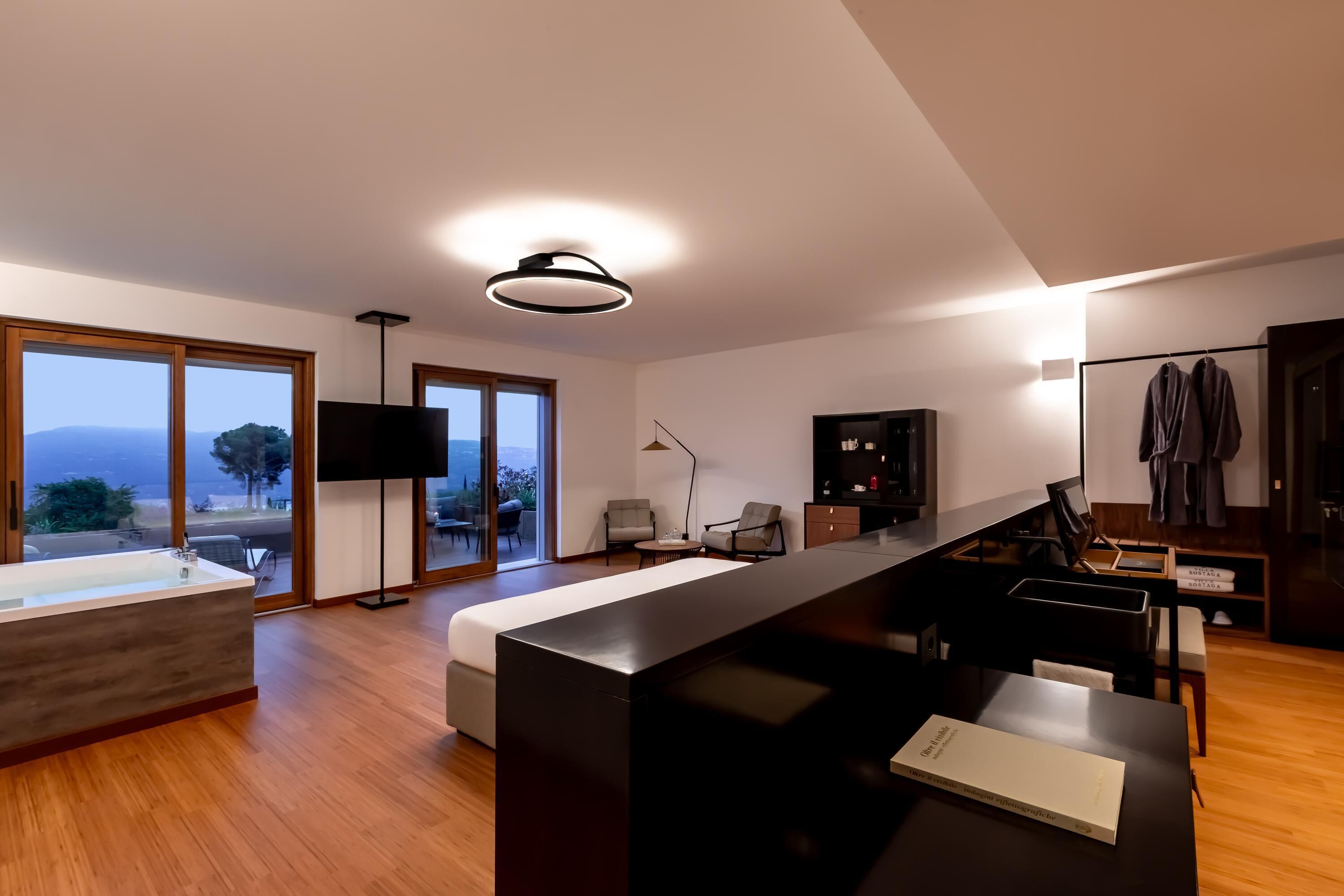 A modern living room with a large window, a black sofa, a coffee table, and a flat-screen TV.