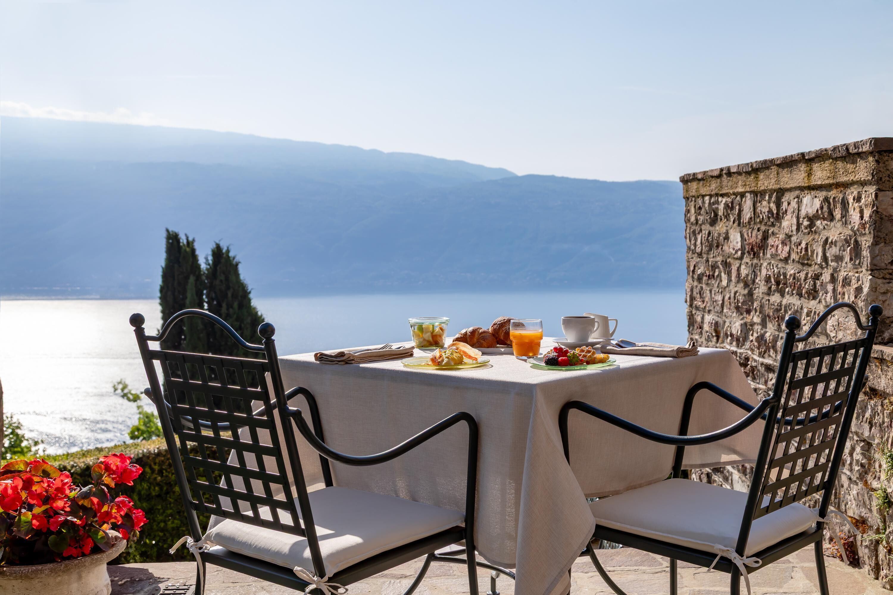 A table set for breakfast with a view of a lake and mountains.