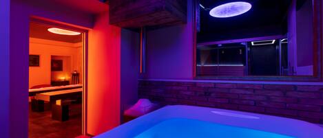 Ein moderner Spa-Bereich mit Whirlpool, Holzboden und Blick auf einen Essbereich.