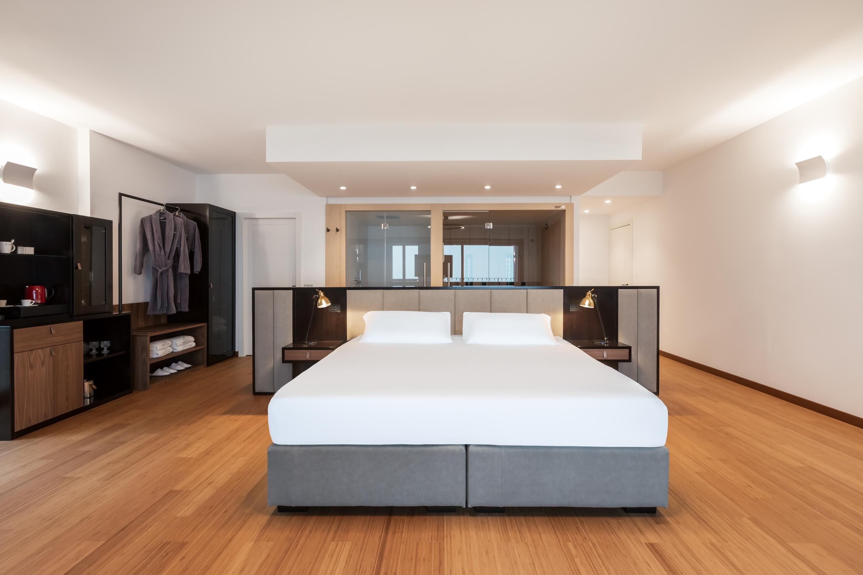 A modern bedroom with a large bed, bedside tables, a wardrobe, and a mirror.