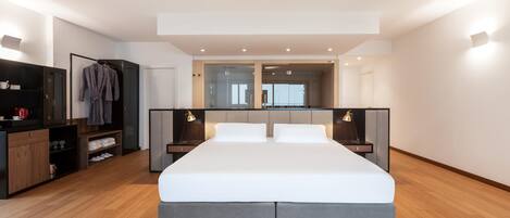 A modern bedroom with a large bed, bedside tables, a wardrobe, and a mirror.