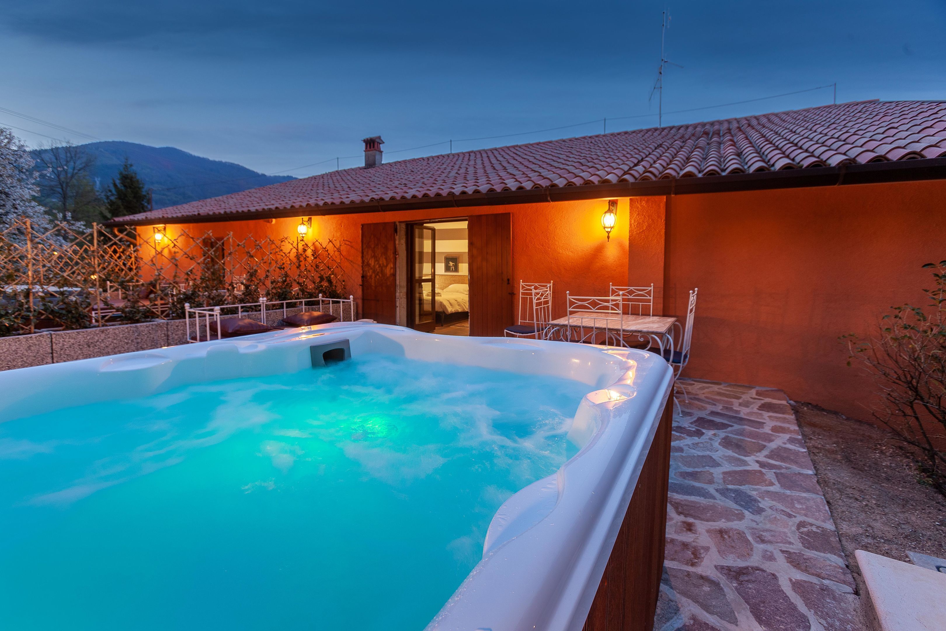 Un bain à remous avec une terrasse en pierre, une plateforme en bois et une vue imprenable sur les montagnes.