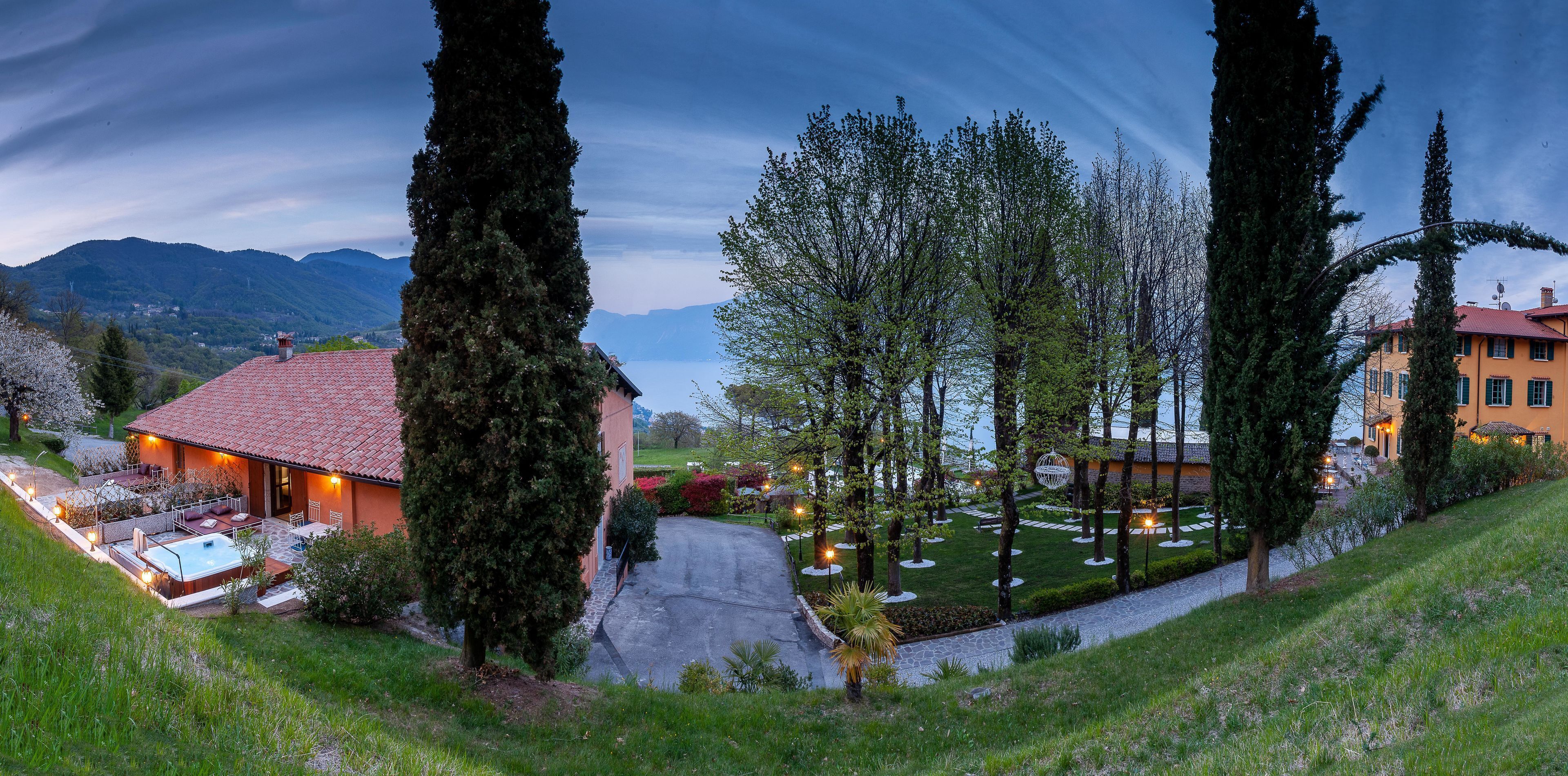 Vue sur une propriété située sur une colline, avec une piscine, un jacuzzi et un jardin bien entretenu, agrémenté d’arbres et d’arbustes.