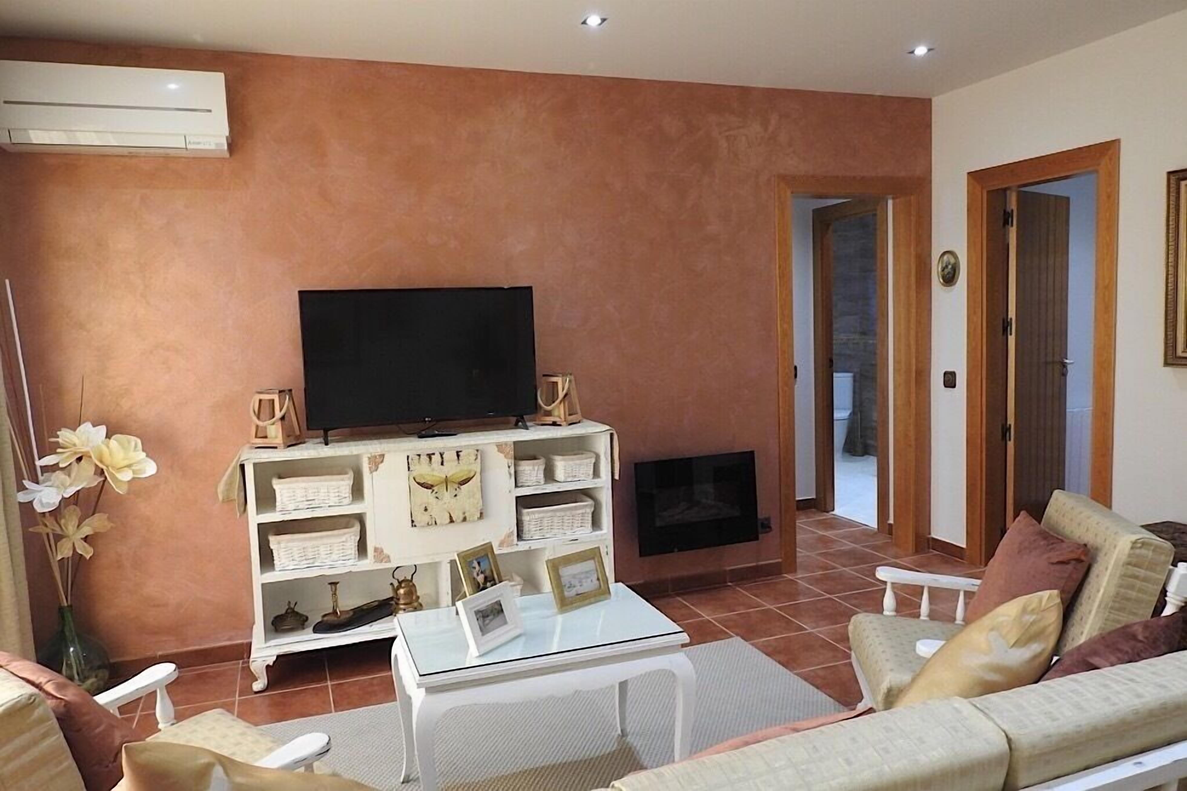 A living room with a flat-screen TV on a white stand, a fireplace, and a sofa.