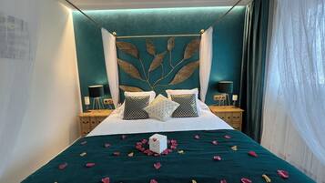 A neatly made bed with a teal bedspread, decorative pillows, and a white box on the bed.