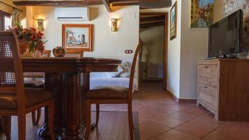 Una habitación acogedora con una mesa de comedor de madera, sillas, una cama y un televisor sobre un mueble de madera.