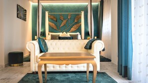 Une chambre à coucher avec un lit à baldaquin, un canapé capitonné, une table basse en bois et un mur d’accent vert.