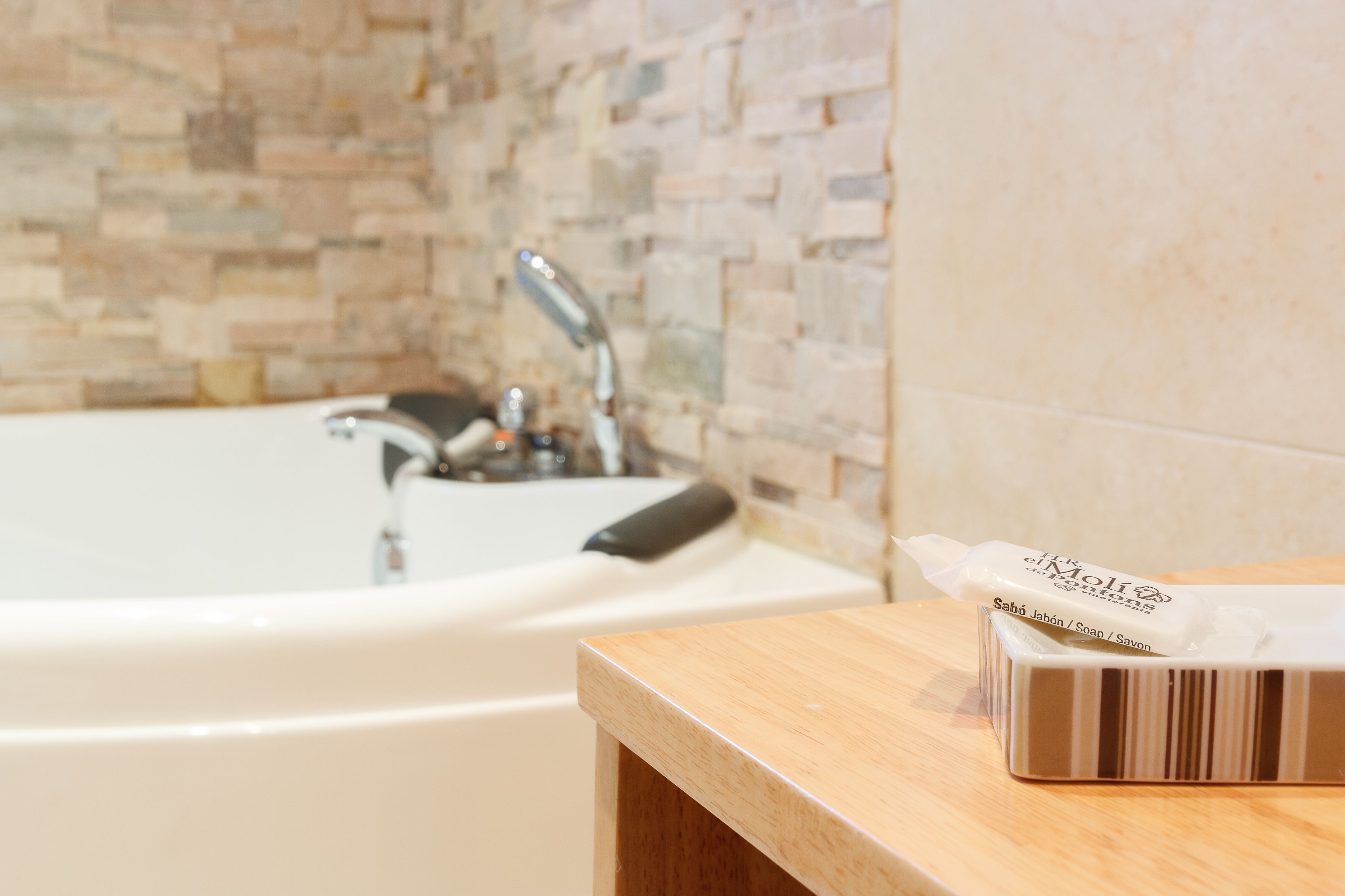 A bathroom with a bathtub, a wooden vanity, and a soap dispenser.
