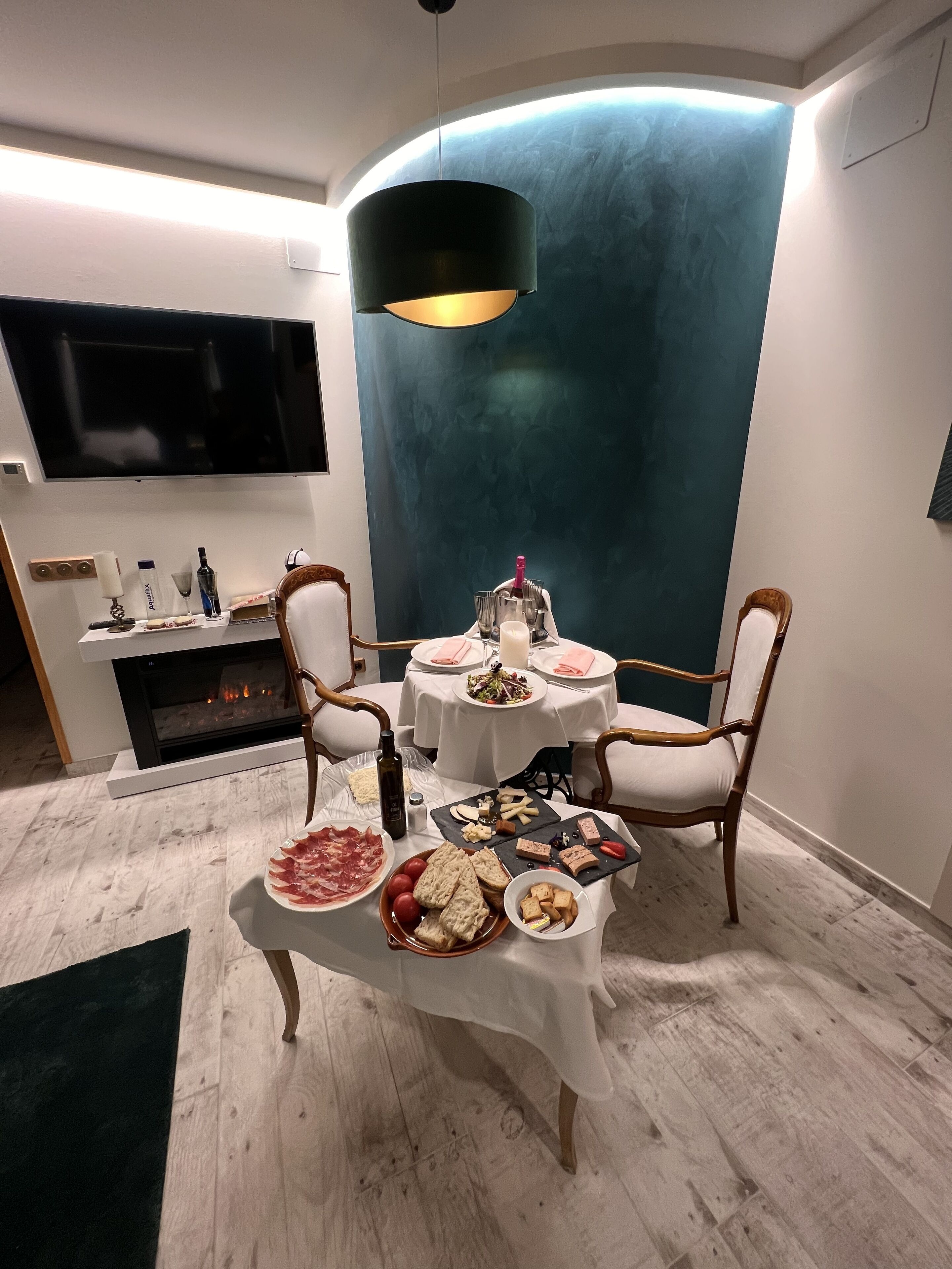 Uma sala de jantar com lareira, duas mesas redondas e uma parede azul marcante.