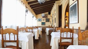 A restaurant with wooden chairs and tables, a tiled floor, and a chandelier.