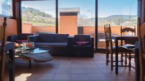 Une terrasse ensoleillée avec un canapé, des fauteuils et une table.