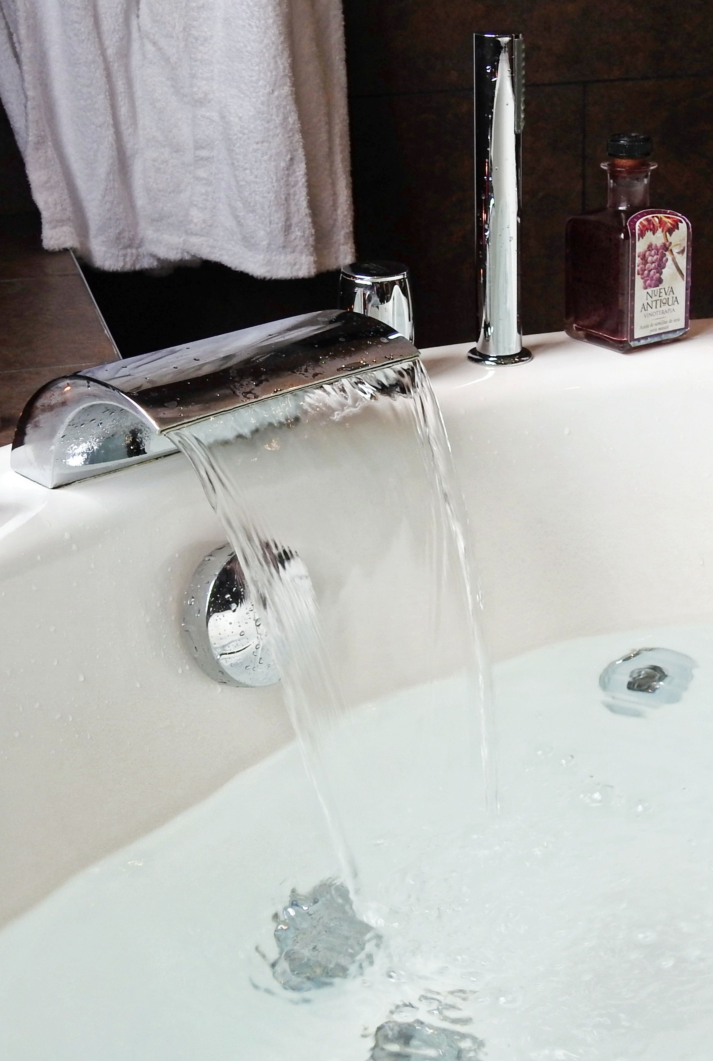 A bathroom with a modern faucet and a bottle of liquid soap on the sink.
