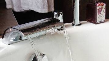A bathroom with a modern faucet and a bottle of liquid soap on the sink.