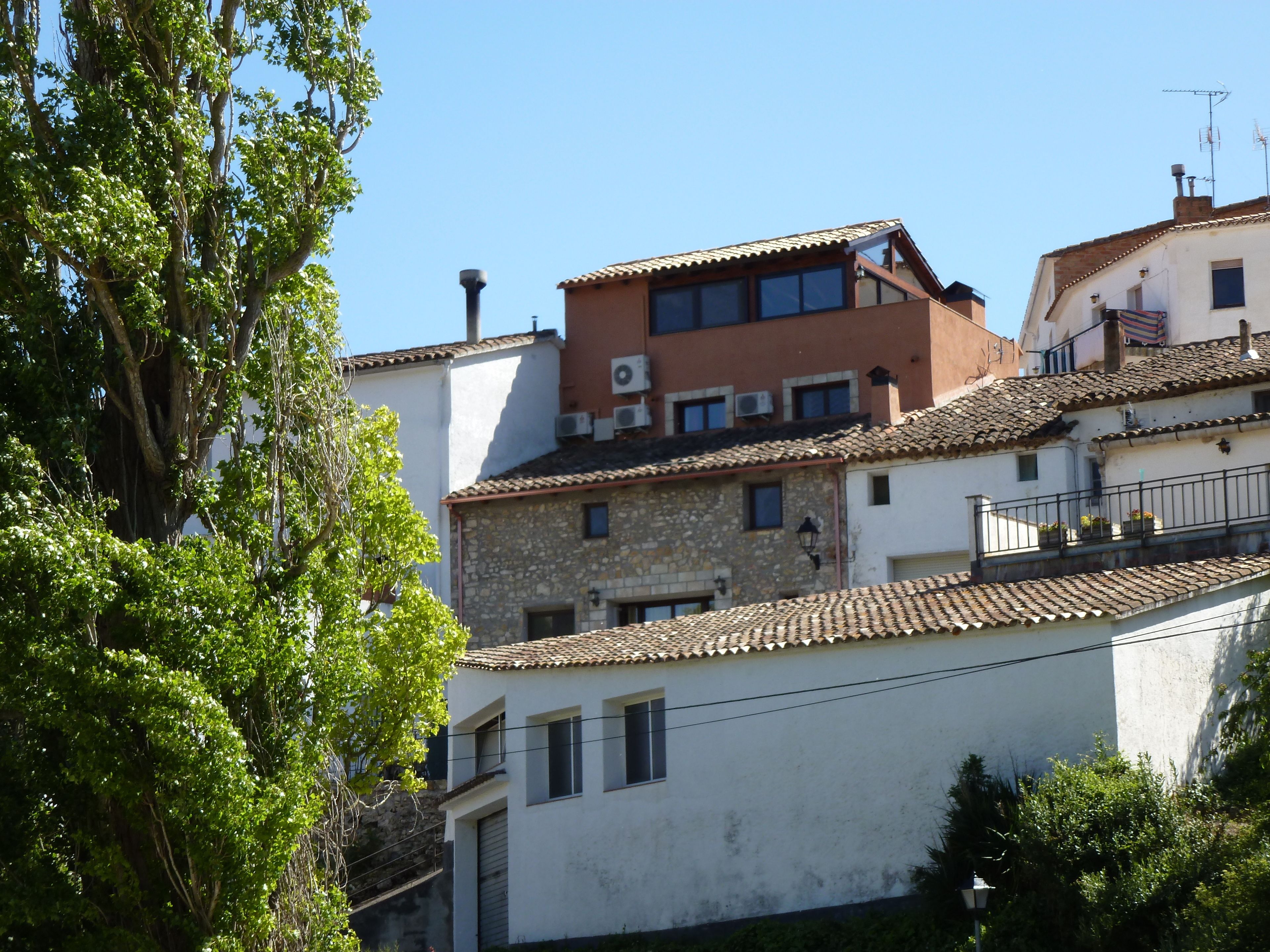A multi-story building with a mix of stone and plaster exteriors, featuring a tiled roof and multiple windows.