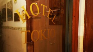 Ein Hotel Eingang mit einer Holztür und dem Schriftzug "HOTEL TOKYO" in großen Lettern.
