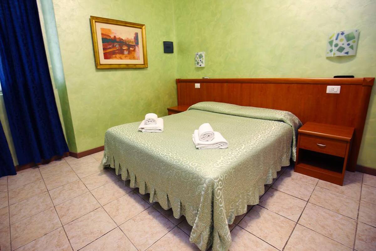 Une chambre avec un lit, une table de chevet, une tête de lit en bois, un tableau et une horloge murale.