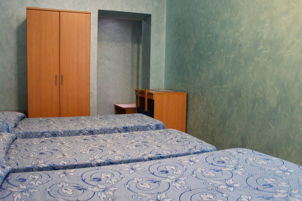 Une chambre avec deux lits, une armoire en bois et un bureau.