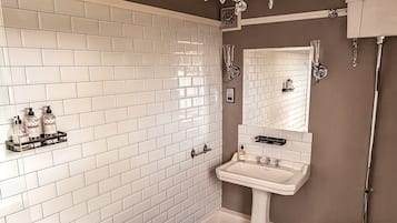 Un baño con una bañera blanca, un lavabo pedestal, un inodoro y una araña.