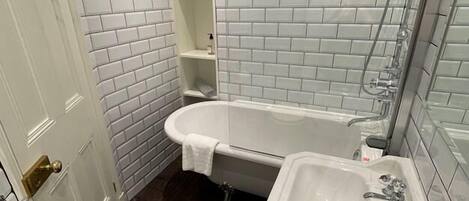 A bathroom with white subway tiles, a bathtub, a sink, and a toilet.