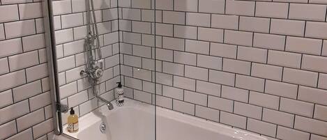 Un baño con una bañera independiente, ducha con mampara de vidrio y suelo de baldosas con diseño de estrellas.