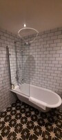 A bathroom with a freestanding bathtub, a glass-enclosed shower, and a tiled floor with a star pattern.