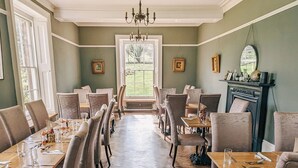 A dining room with a long table, multiple chairs, a chandelier, and a fireplace. - Oakhill  (Matlock)