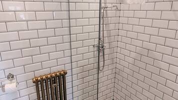 A bathroom with white subway tile walls, a black and white star-patterned floor, a toilet, and a shower with a towel rack.