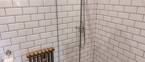 A bathroom with white subway tile walls, a black and white star-patterned floor, a toilet, and a shower with a towel rack.