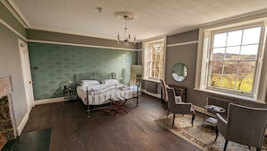 A bedroom with a bed, a chair, a table, a mirror, and a view of the outdoors. - Oakhill  (Matlock)