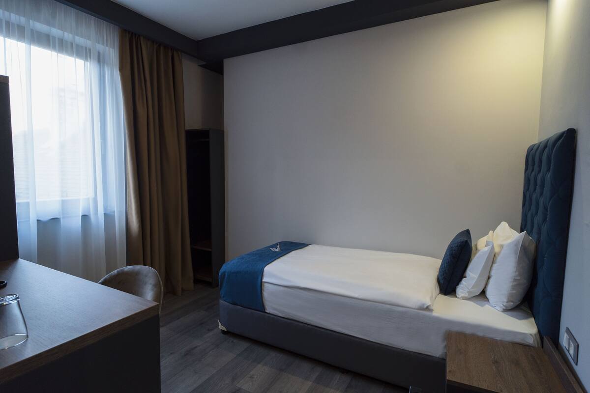 A hotel room with a bed, a desk, and a chair.