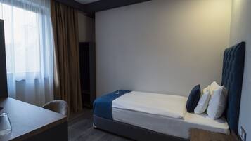 Una camera d'albergo con un letto, una scrivania e una sedia.