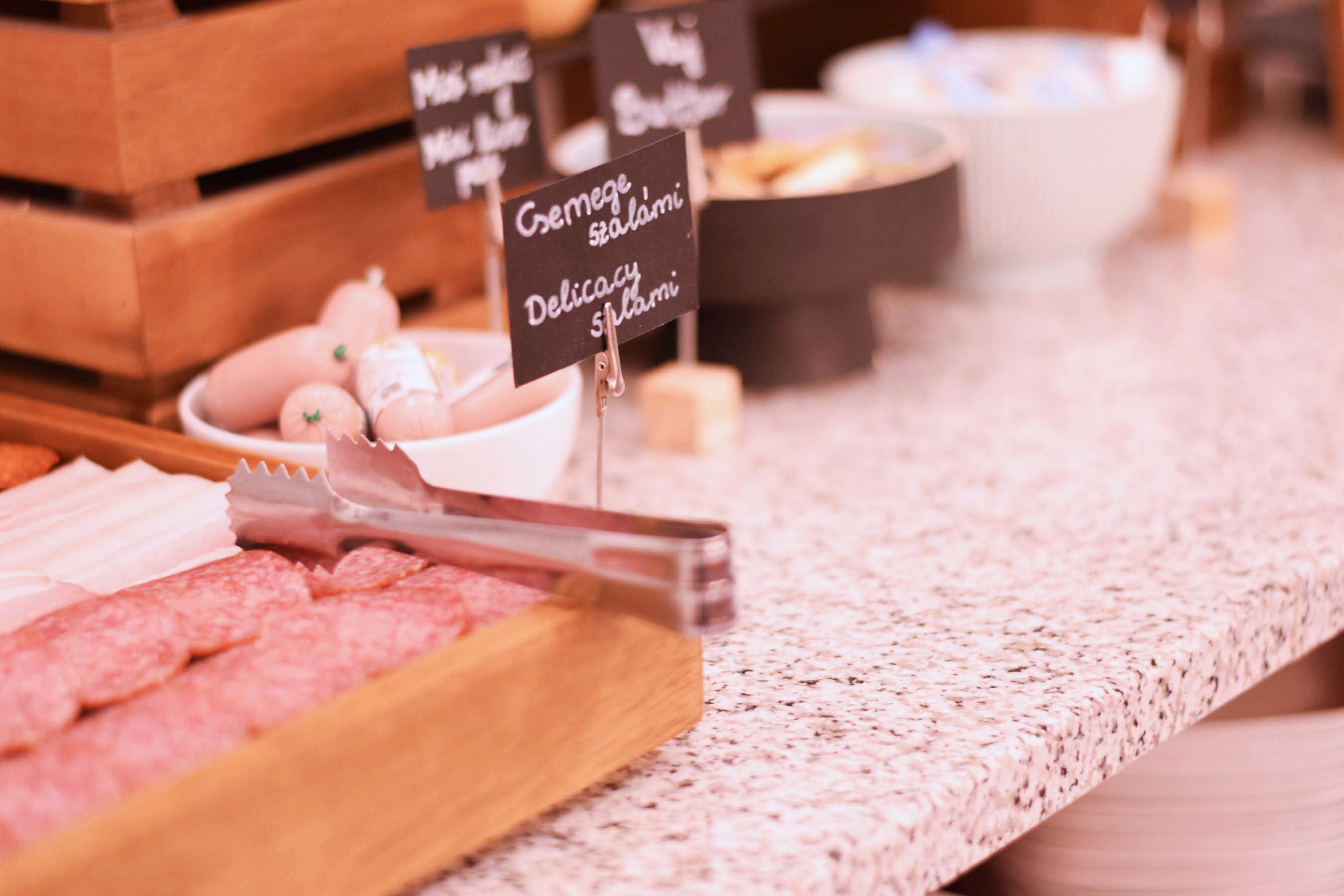 A deli counter with various meats and cheeses, including salami and prosciutto, displayed on a wooden board.