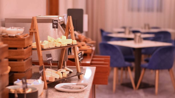 A breakfast buffet with cheese and other items, wooden furniture, and a seating area with tables and chairs.