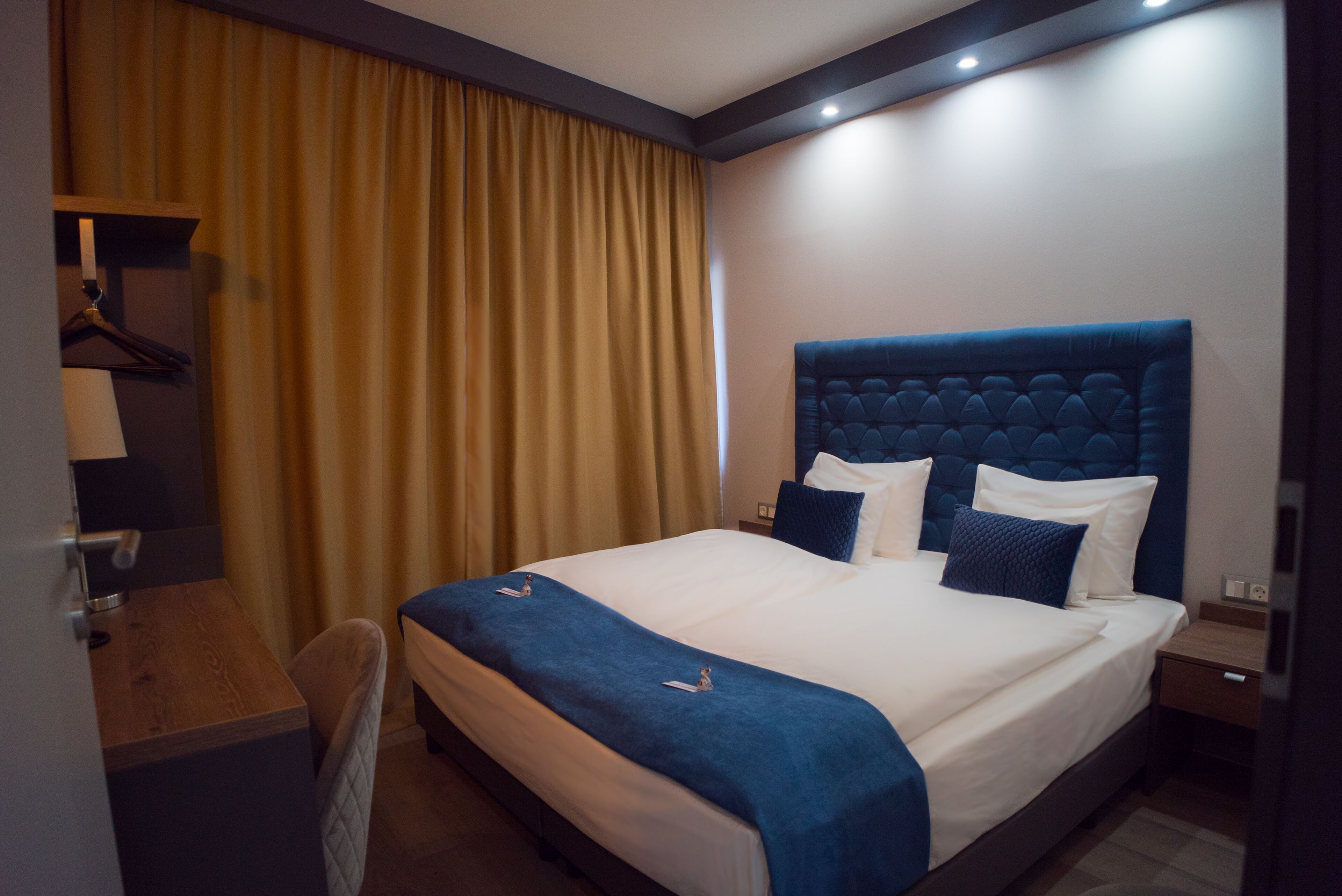 Una habitació d'hotel amb un llit gran, una taula de treball i una cadira.