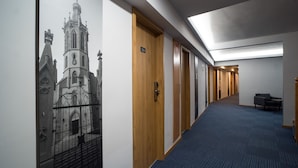 A hallway with a blue carpet, wooden doors, and a wall mural of a church.