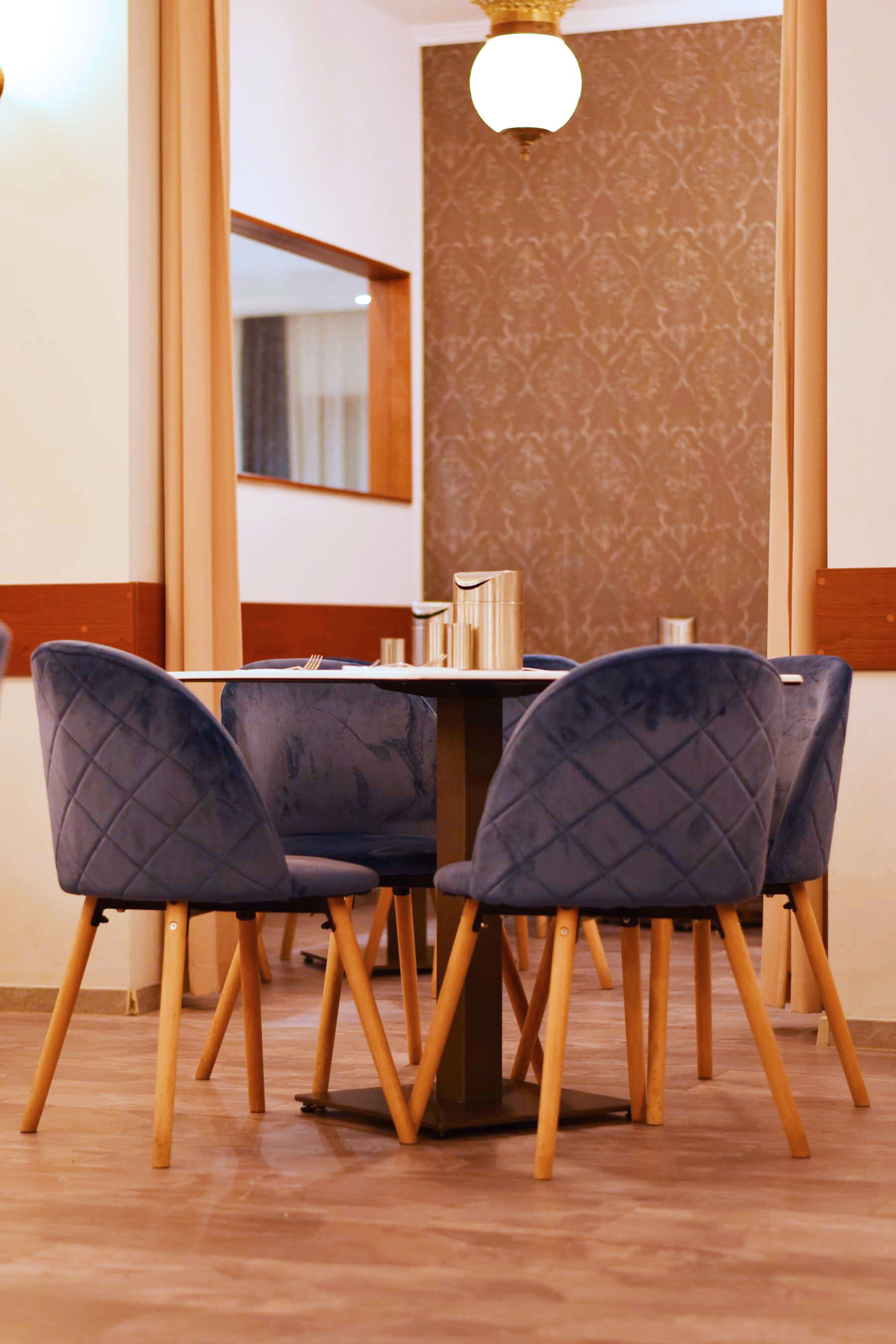 A dining area with a table set for four, surrounded by four chairs with a quilted design.