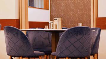 A dining area with a table set for four, surrounded by four chairs with a quilted design.