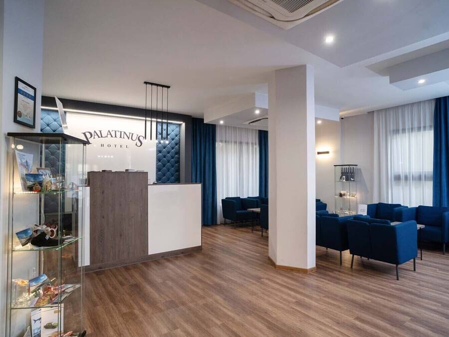 Um hall de hotel moderno, com balcão de recepção, área de estar e uma vitrine de vidro.