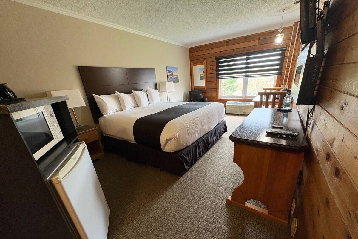 Una habitación de hotel con cama, escritorio, microondas y televisión.