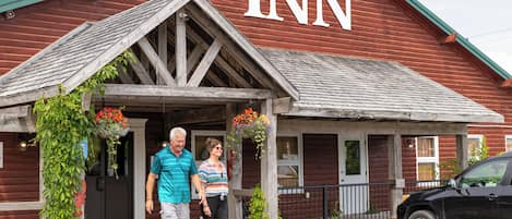 A rustic building with a prominent "INN" sign, wooden beams, and a porch with hanging flower baskets.